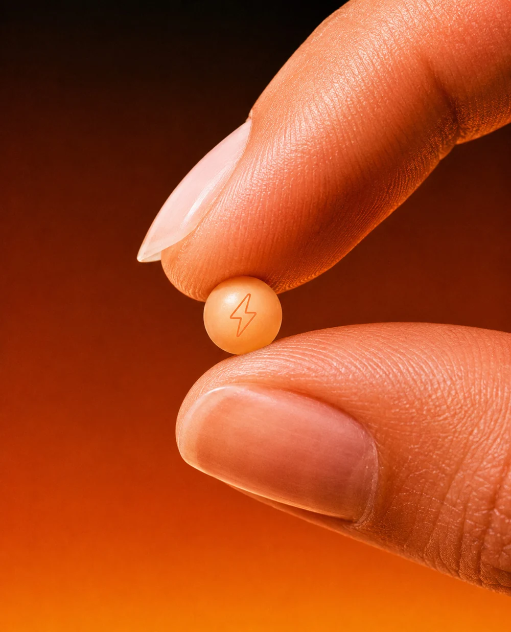 A small orange NRGZ pearl held between two fingertips